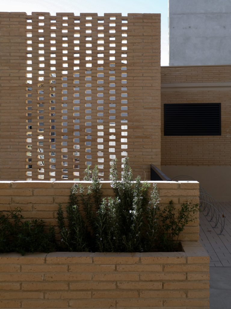 outside patio with brick wall with an open structure and low wall with plants in front