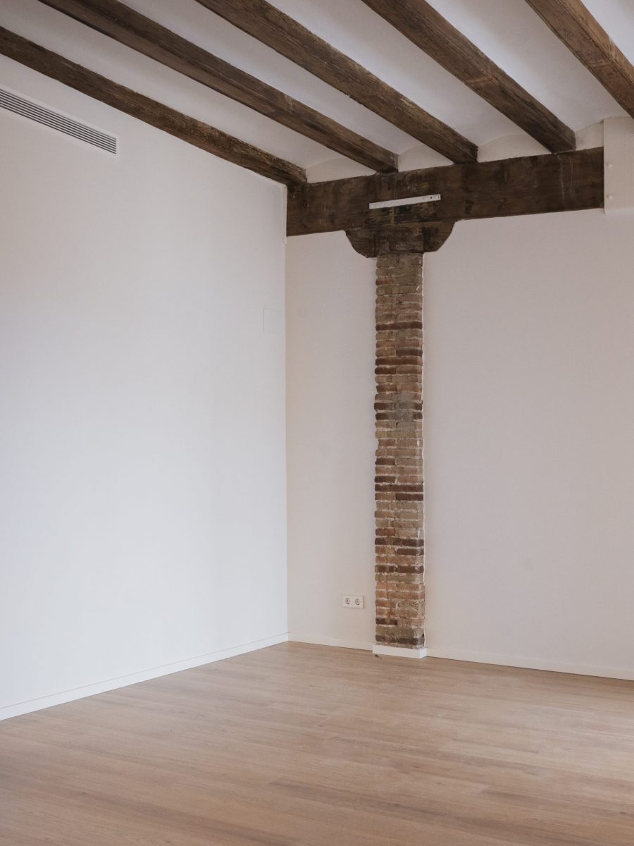 room with old elements like wooden beams at ceiling and stone pillar in wall