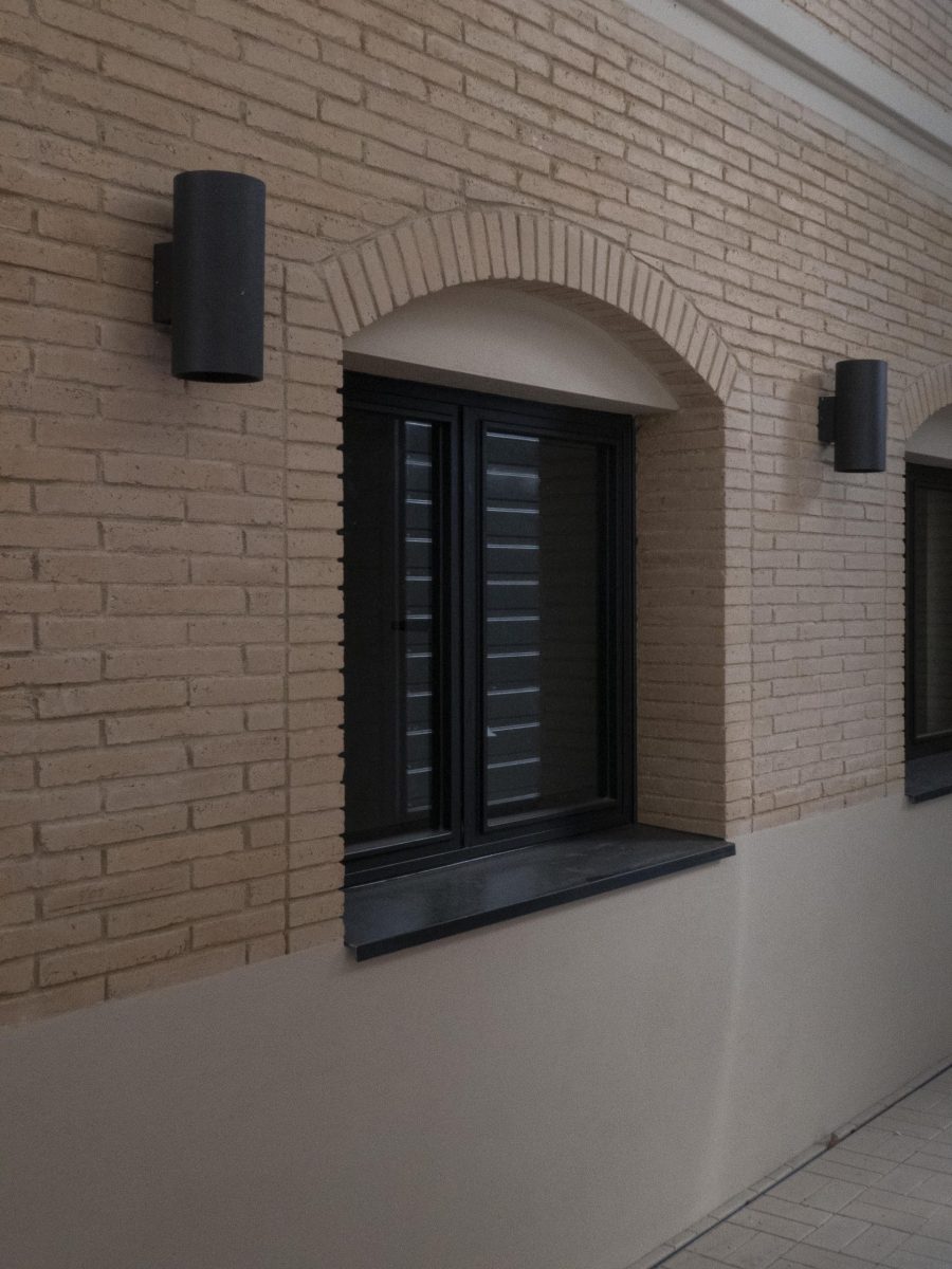 half round window in beige brick wall building with lights on both sides